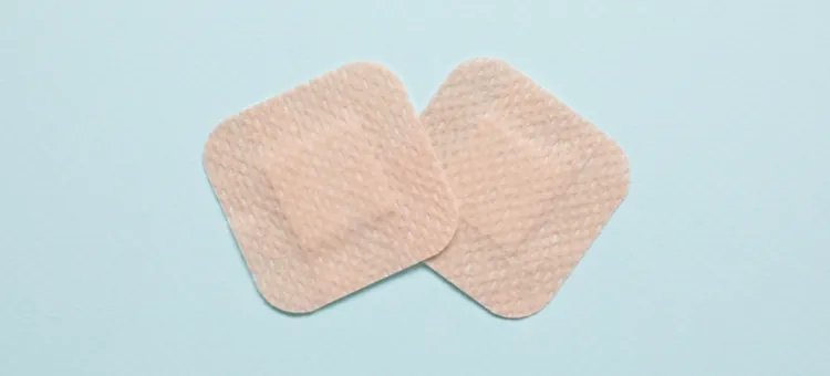 Plastry antykoncepcyjne – jak działają? Najczęściej zadawane pytania Dwa beżowe plasterki antykoncepcyjne na błękitnej powierzchni