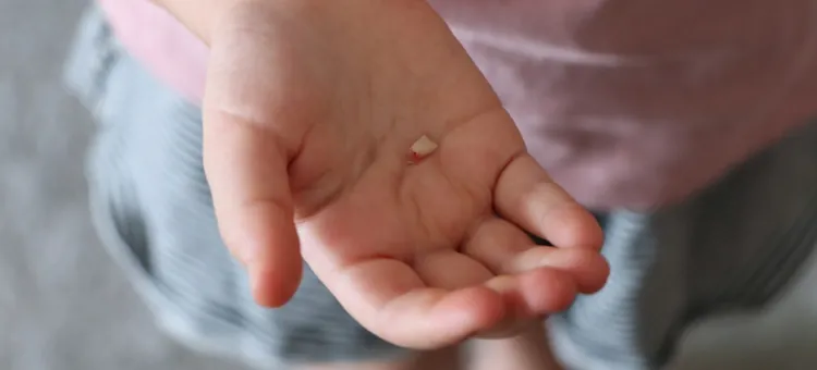 Kiedy wypadają mleczaki? Szczęśliwe dziecko w niebieskiej koszulce prezentuje ubytek w swoim uzębieniu