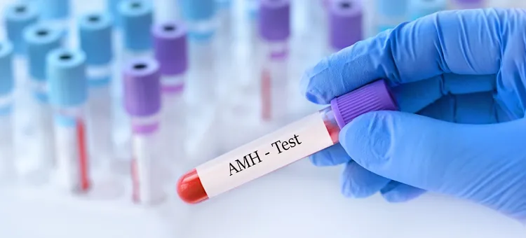 Krew w probówce z napisem "AMH - Test", trzymanej przez rękę w niebieskiej rękawiczce, pobrana do analizy hormonu AMH w laboratorium