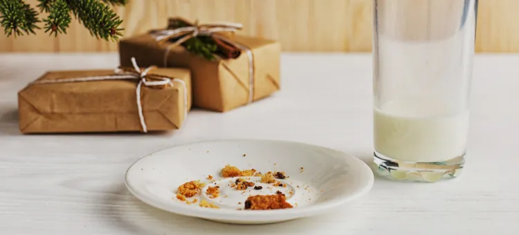 Gotowe usługi, aplikacje i AI – narzędzia, które pomogą zorganizować najbardziej magiczny „dowód” wizyty Mikołaja Okruszki słodkiego deseru i niepełna szklanka mlecznego napoju na stole, za nimi czekają świąteczne upominki