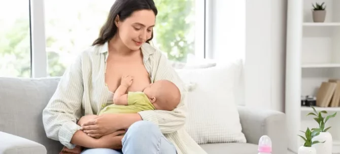 Czuła matka karmi swoje niemowlę piersią, siedząc na kanapie