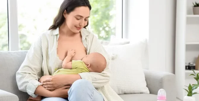 Czuła matka karmi swoje niemowlę piersią, siedząc na kanapie