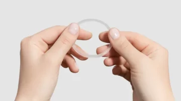 Kobiece dłonie trzymają elastyczny, jasny antykoncepcyjny krążek dopochwowy