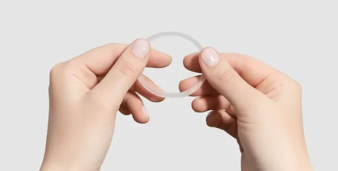 Kobiece dłonie trzymają elastyczny, jasny antykoncepcyjny krążek dopochwowy