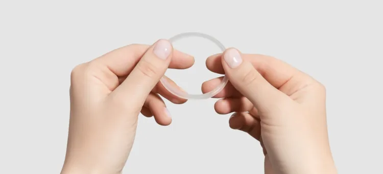 Kobiece dłonie trzymają elastyczny, jasny antykoncepcyjny krążek dopochwowy