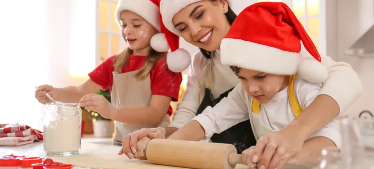 Kruche ciasteczka maślane, które możesz przygotować z dziećmi Uśmiechnięta kobieta z dwójką dzieci przygotowujący wspólnie świąteczne ciastka