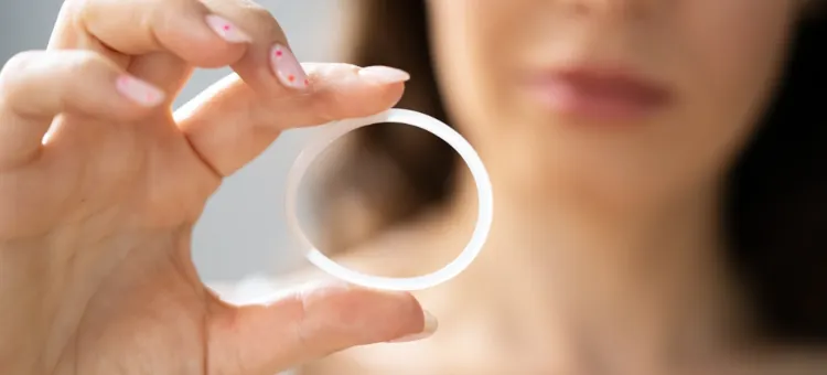 FAQ Dłoń kobiety delikatnie trzyma w palcach przezroczysty krążek dopochwowy