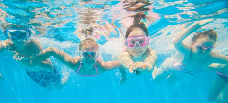 Z jakich ulg i zniżek dla rodzin wielodzietnych można korzystać? Radośnie nurkujące dzieci w błękitnej wodzie basenu