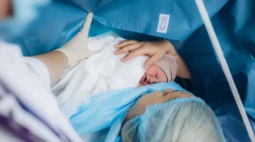 Kobieta czule wita swe nowo narodzone niemowlę w sali operacyjnej