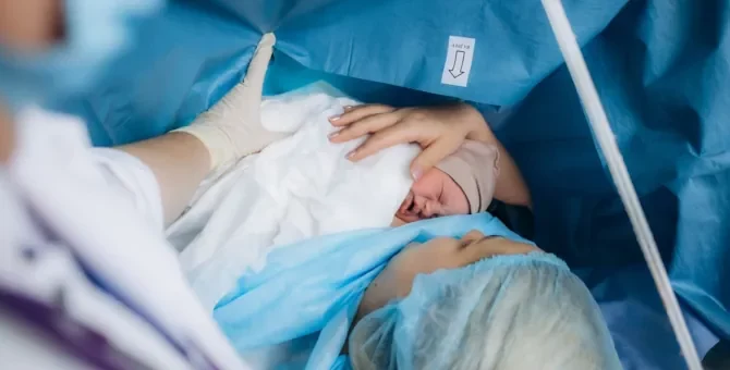 Kobieta czule wita swe nowo narodzone niemowlę w sali operacyjnej