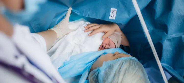 Kobieta czule wita swe nowo narodzone niemowlę w sali operacyjnej