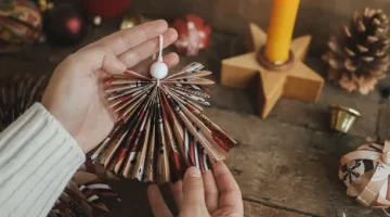 Kobiece dłonie prezentują uroczego aniołka z ręcznie złożonego papieru