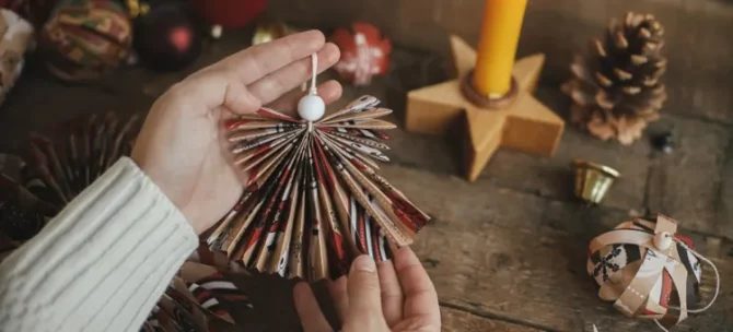 Kobiece dłonie prezentują uroczego aniołka z ręcznie złożonego papieru