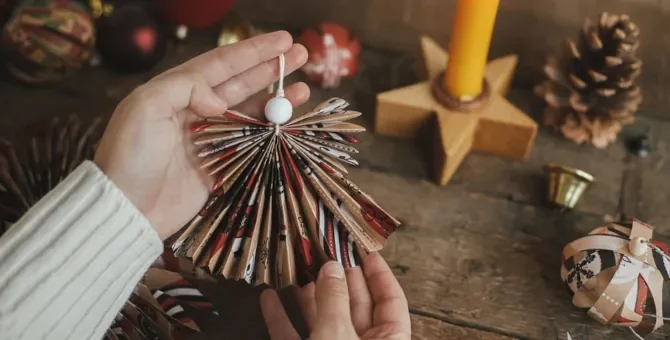 Kobiece dłonie prezentują uroczego aniołka z ręcznie złożonego papieru