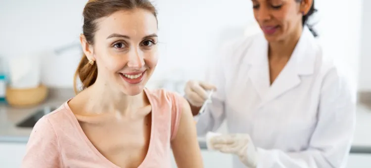 Młoda pacjentka z promiennym uśmiechem otrzymuje zastrzyk antykoncepcyjny od medyka