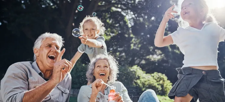 Szczęśliwa rodzina, dziadkowie i wnuczęta, rozkoszują się letnim dniem puszczając mydlane bańki