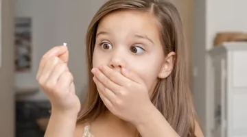 Wielkie zdziwienie małego dziecka trzymającego w dłoni wypadły ząbek