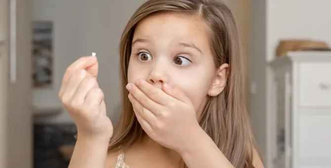 Wielkie zdziwienie małego dziecka trzymającego w dłoni wypadły ząbek