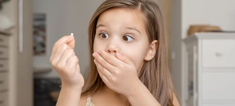 Wielkie zdziwienie małego dziecka trzymającego w dłoni wypadły ząbek