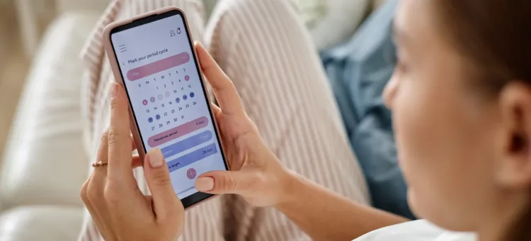 Kobieta planująca swój cykl miesiączkowy przez aplikację na smartfonie