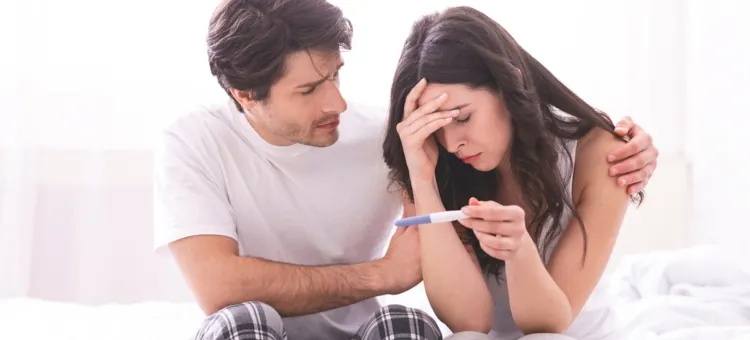Zestresowana partnerka trzymająca domowy test ciążowy, pocieszana przez zatroskanego mężczyznę