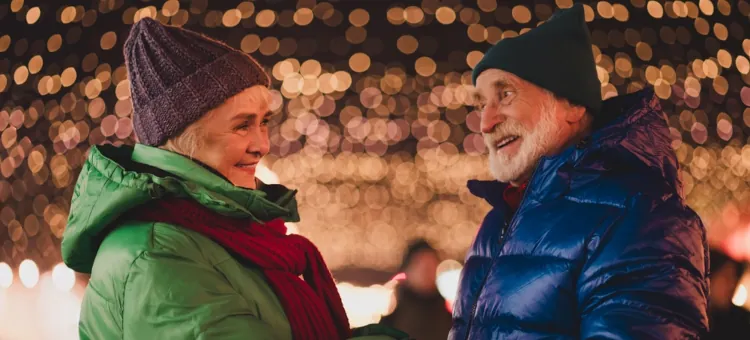 Wiekowe małżeństwo z czułością rozmawia przy klimatycznym, rozmazanym tle miejskich iluminacji