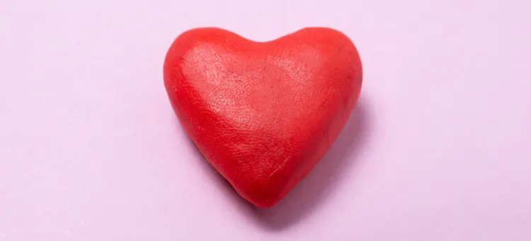 Plastyczny, czerwony obiekt w kształce serca na jasnoróżowym podkładzie