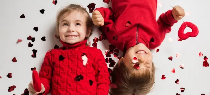 Roześmiane maluchy radują się wśród rozsypanych walentynkowych serduszek