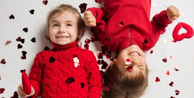 Roześmiane maluchy radują się wśród rozsypanych walentynkowych serduszek