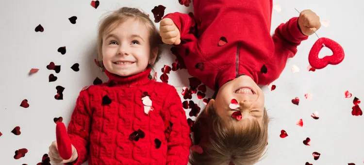Roześmiane maluchy radują się wśród rozsypanych walentynkowych serduszek