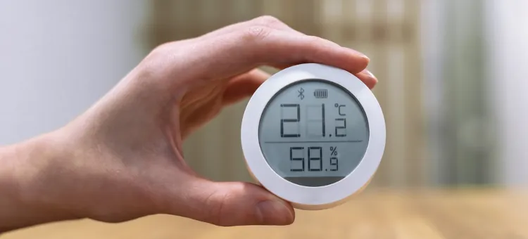W dłoni trzymane jest cyfrowe urządzenie wskazujące wilgotność i temperaturę powietrza w pomieszczeniu