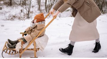 dziecko siedzące w sankach z oparciem na spacerze