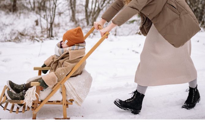 dziecko siedzące w sankach z oparciem na spacerze