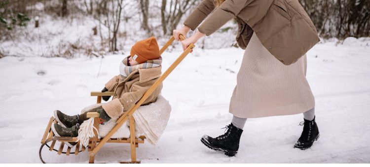 dziecko siedzące w sankach z oparciem na spacerze