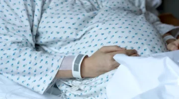 Pacjentka w jasnej piżamie na szpitalnym łóżku wyczekuje przyjścia na świat swojego maleństwa