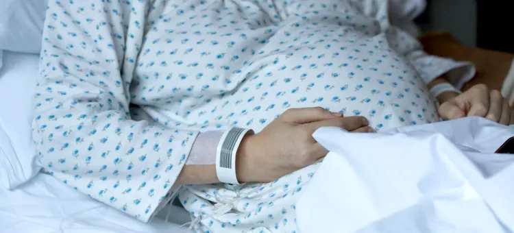 Pacjentka w jasnej piżamie na szpitalnym łóżku wyczekuje przyjścia na świat swojego maleństwa