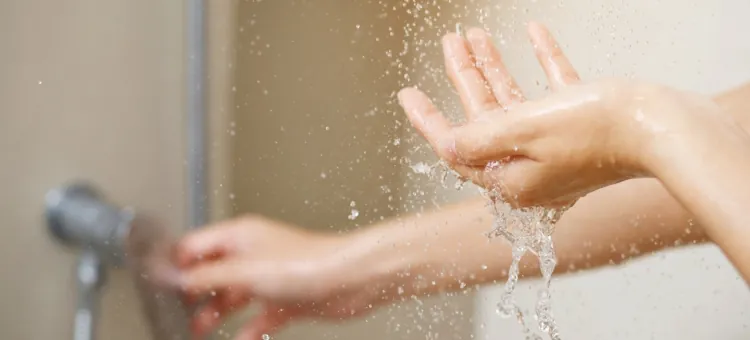 Strumień świeżej wody z prysznica ożywia ręce podczas higieny ciała