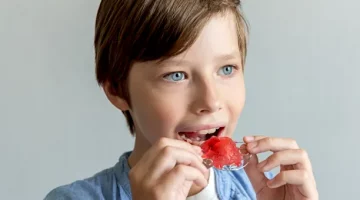 Młody chłopiec starannie dopasowuje swoją ruchomą szczękę ortodontyczną do ust