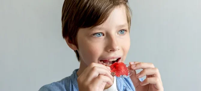 Młody chłopiec starannie dopasowuje swoją ruchomą szczękę ortodontyczną do ust