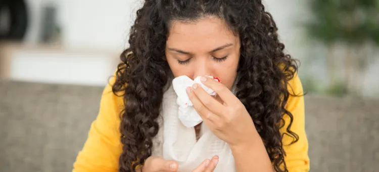 Młoda kobieta powstrzymuje upływ krwi z nosa chusteczką