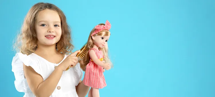 Radosna dziewczynka z czułością układa pukle blond lalki na jasnoniebieskim niebieskim tle