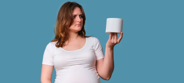 Przyszła matka, zamyślona, oglądająca białą rolkę papieru toaletowego, na niebieskim tle