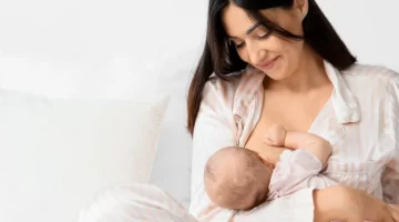 Młoda matka na jasnym tle z czułością zapewnia pokarm swojemu nowo narodzonemu dziecku, karmiąc piersią