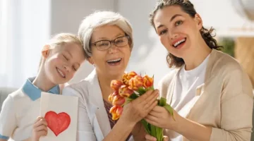 Radosna babcia ze wnuczką i córką świętujące wspólną chwilę z pięknym bukietem tulipanów