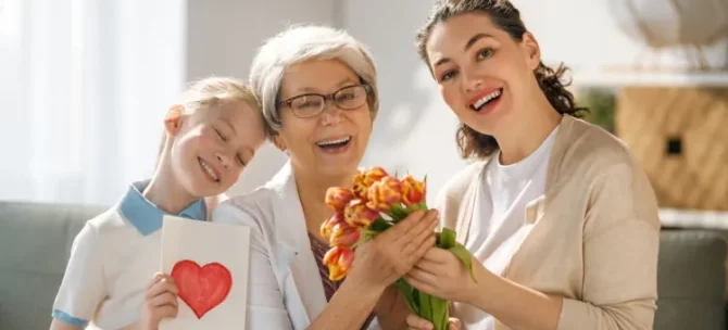 Radosna babcia ze wnuczką i córką świętujące wspólną chwilę z pięknym bukietem tulipanów