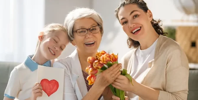 Radosna babcia ze wnuczką i córką świętujące wspólną chwilę z pięknym bukietem tulipanów