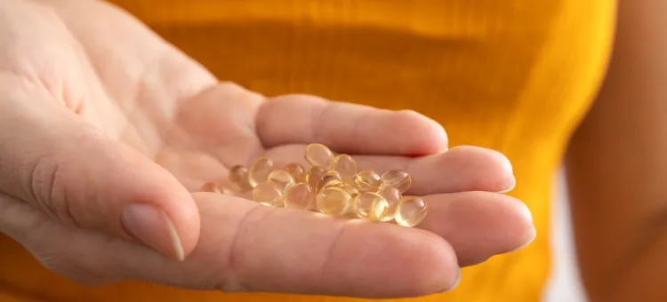 FAQ Jasnożółte, przezroczyste kapsułki z suplementami diety delikatnie spoczywające w dłoni na tle żółtej bluzki