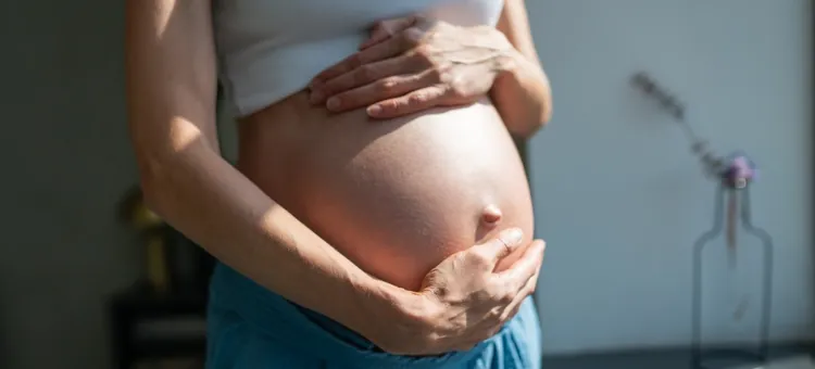 Katar w ciąży – czy stanowi zagrożenie dla mamy i dziecka? Przyszła mama z miłością dotyka swojego powiększonego brzuszka w słońcu, zbliżenie dłoni i brzucha