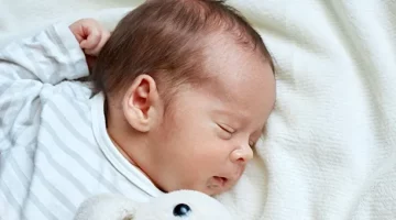 Niemowlę spokojnie odpoczywa na jasnym, miękkim posłaniu