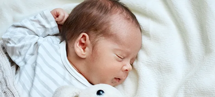 Niemowlę spokojnie odpoczywa na jasnym, miękkim posłaniu